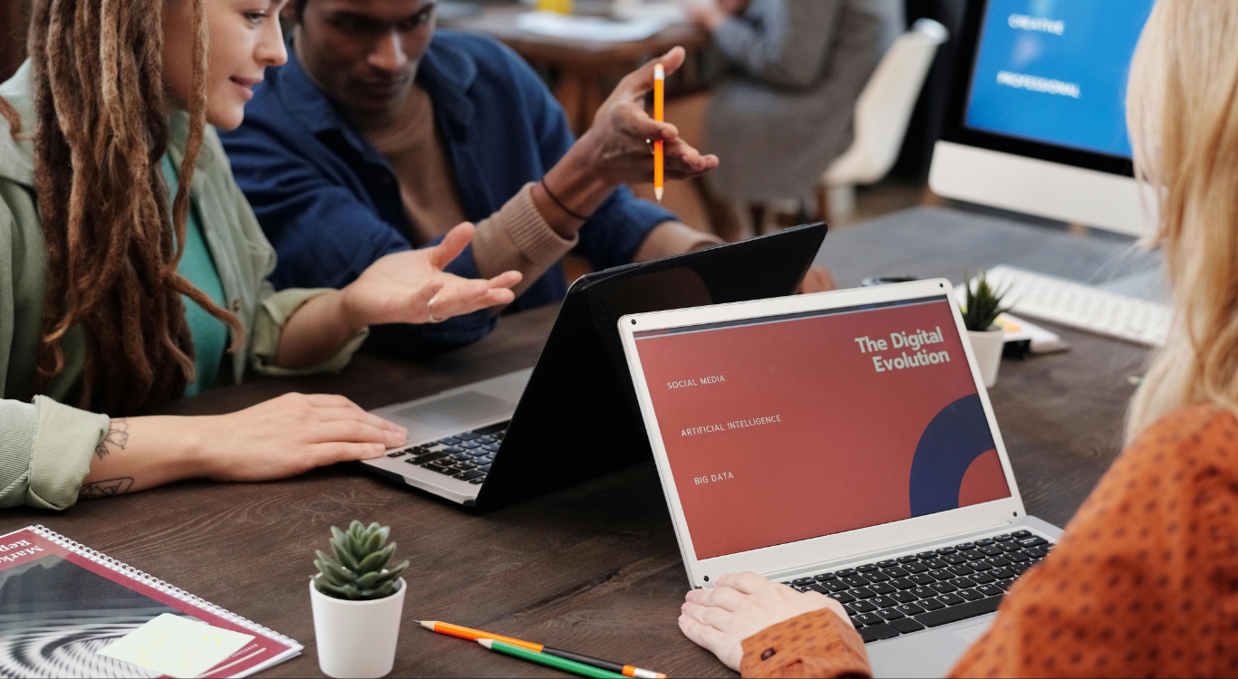 A collaborative team meeting at IDK Solutions, where strategists discuss digital planning around a laptop screen titled 'The Digital Evolution,' featuring topics like social media, artificial intelligence, and big data.